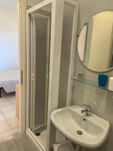 ein Bad mit einem Waschbecken, einem Spiegel und einer Dusche in der Unterkunft Baia dei Gabbiani in San Lorenzo al Mare