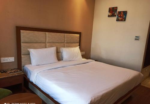 a bed in a hotel room with white sheets and pillows at Maple Grand in Agra