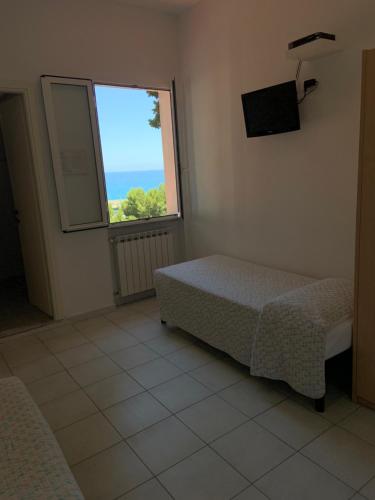 Schlafzimmer mit einem Bett und einem Fenster in der Unterkunft Baia dei Gabbiani in San Lorenzo al Mare