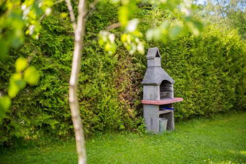 a small stone bird house sitting in the grass at Domki nad stawem. in Polańczyk