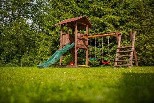 a playground with a slide and a swing at Domki nad stawem. in Polańczyk