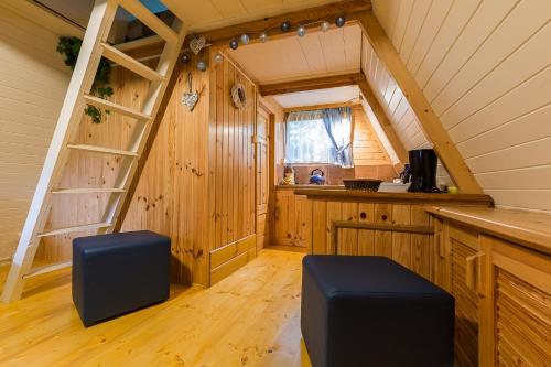 an attic room with a ladder and a kitchen at Domki nad stawem. in Polańczyk