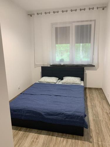 a bedroom with a bed with blue sheets and a window at Yacht Club Apartamenty in Radzyń