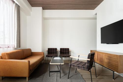 a living room with a couch and a table and chairs at Nest Hotel Hiroshima Ekimae in Hiroshima