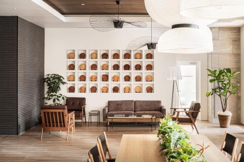 a living room with a couch and tables at Nest Hotel Hiroshima Ekimae in Hiroshima