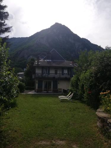 a large house with a mountain in the background at Le domaine des 3 marmottes Chambres d' hôtes in Cierp