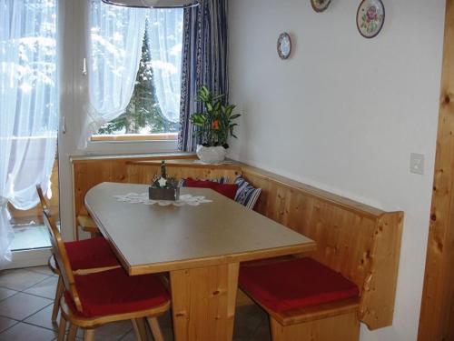 a dining room table and chairs with a table and a window at Chasa Mezpra/Stephan Jenal Nr. 1 - Ferienwohnung für 2-4 Personen in Compatsch