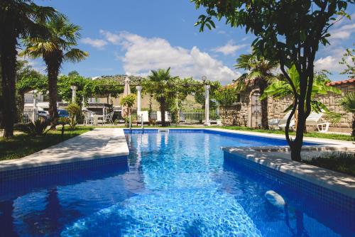 a swimming pool with blue water and palm trees at Kazablanka Rooms Aerodrom in Podgorica