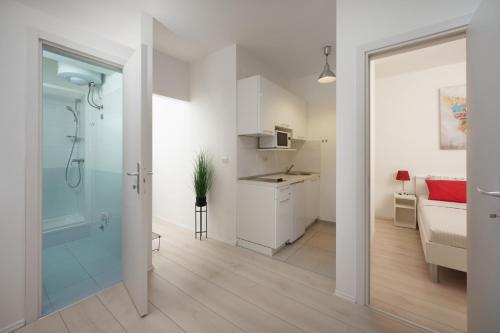 Biała łazienka z prysznicem i kuchnia w obiekcie Apartments Antons 2 w Puli