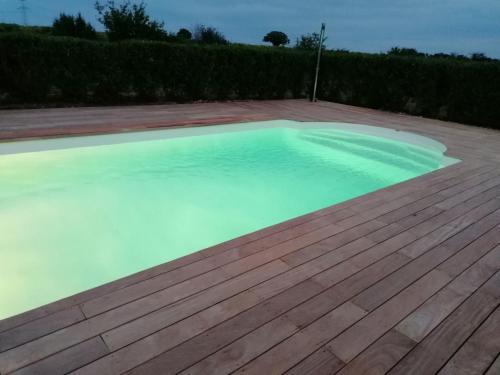 une grande piscine avec une terrasse en bois dans l'établissement le domaine de bellevue, à Tanzac