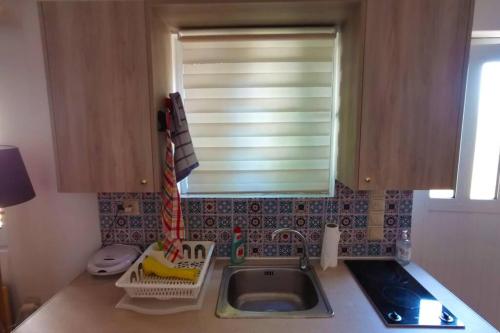 a kitchen counter with a sink and a window at Cosy guest house with private yard in Saronida