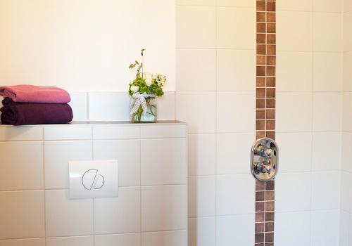 a bathroom with a shower with white tiles at WELTRAD Am Fluß Restaurant & Quartier in Schönebeck