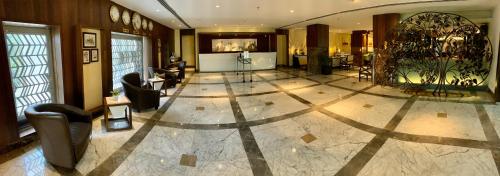 a lobby with a large room with chairs and tables at Vivanta Vadodara in Vadodara
