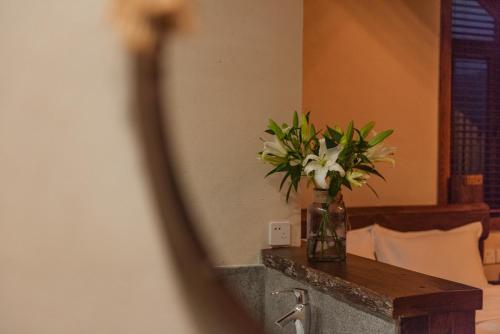 un jarrón de flores sobre una mesa en una habitación en Mohe Hostel en Deqing