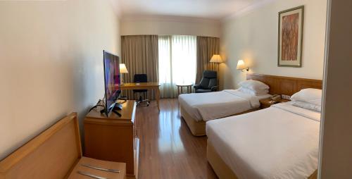 a hotel room with two beds and a television at Vivanta Vadodara in Vadodara