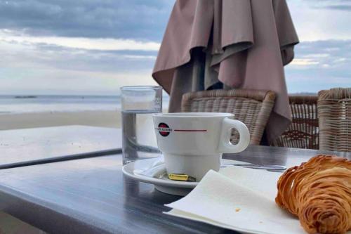 - une table avec une tasse de café et un croissant sur la plage dans l'établissement Petit loft SAINT-MALO intra-muros, à Saint-Malo