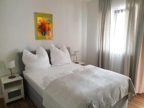 a white bed with white pillows and a window at Catalleya Haus in Langenlois