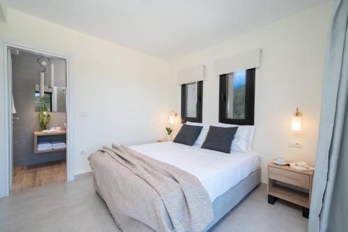 a white bedroom with a large bed and windows at Diosas Luxury Villas in Pilaroú
