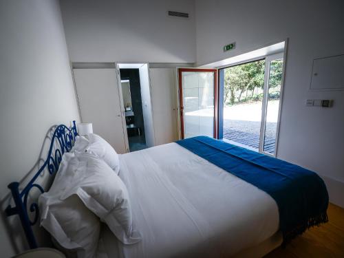 a bedroom with a bed and a large window at Morgadio da Calcada Douro Wine&Tourism in Provesende