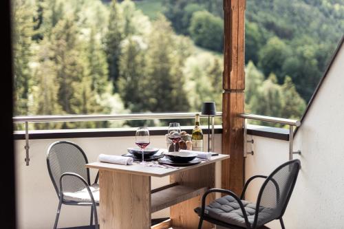a table with two chairs and wine glasses on a balcony at Hotel Berghang in Collepietra