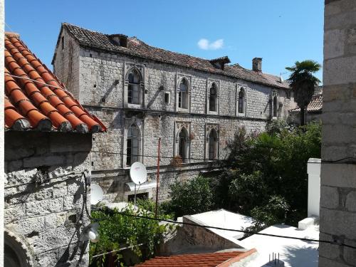 an old stone building with a palm tree in front of it at Rooms & Studio Stipcic in Trogir