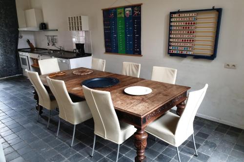 a dining room with a wooden table and white chairs at De Oude School in Visé