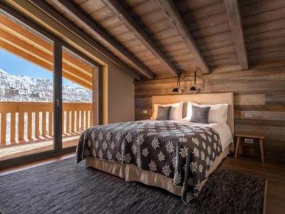 a bedroom with a bed and a large window at La Cresta Chalet in Breuil-Cervinia