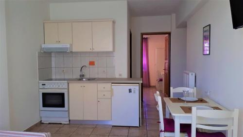 a kitchen with white appliances and a table with chairs at Ikos Studios and Apartments in Patitiri