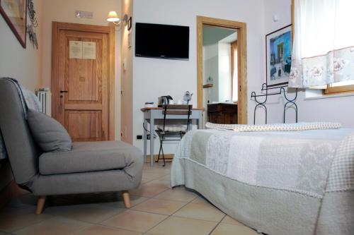 1 dormitorio con silla, 1 cama y TV en Masseria Fontana dei Fieri, en Pietrelcina
