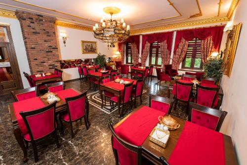 a restaurant with red tables and chairs and a chandelier at Hotel Katerina Sarayı 1877 in Kars