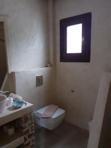 łazienka z toaletą i oknem w obiekcie Superior Suite Cronus w mieście Vassilias