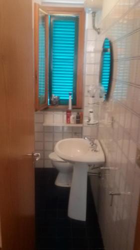 ein Badezimmer mit einem weißen Waschbecken und zwei Fenstern in der Unterkunft Mia House in Porto Vecchio