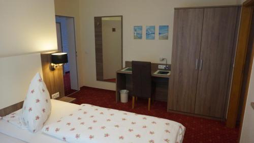 a hotel room with a bed and a desk in it at Hotel Neuses in Cuxhaven