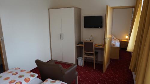a hotel room with a bed and a desk with a television at Hotel Neuses in Cuxhaven