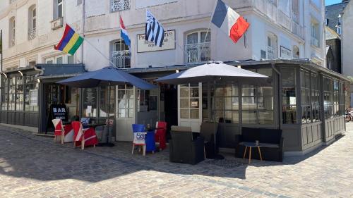 a building with tables and umbrellas on a street at Hôtel La Porte Saint Pierre-Logis Hôtel Intra Muros in Saint Malo