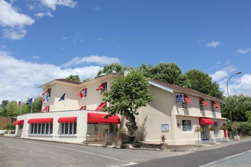 a building with red awnings on a street at Hôtel du Lac d'Arjuzanx in Arjuzanx