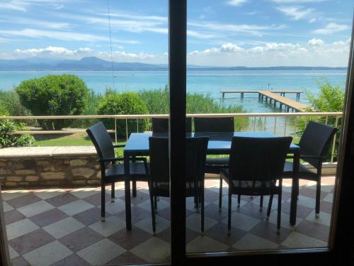 a table and chairs on a balcony with a view of the ocean at Lake Front Luxury Apartment in Sirmione