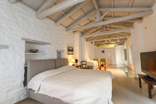 a white bedroom with a bed and a tv at Vita Real Estate in Hydra