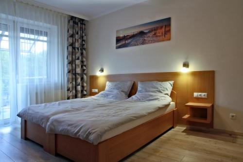 ハイドゥソボスローにあるAqua City Apartmanのベッドルーム1室(大型ベッド1台、木製ヘッドボード付)