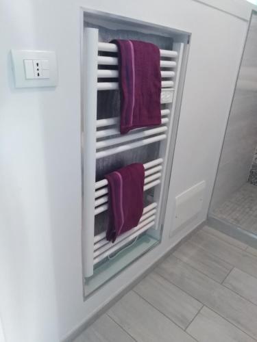 - un porte-serviettes dans la salle de bains avec des serviettes pourpres dans l'établissement Le Palais du Tropique appartement vue mer 5é étage avec ascenseur, à Juan-les-Pins