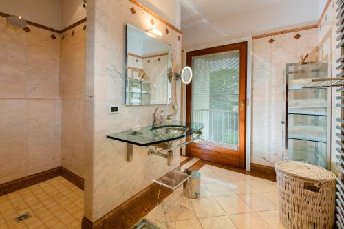 a bathroom with a glass sink and a window at Lake Front Luxury Apartment in Sirmione
