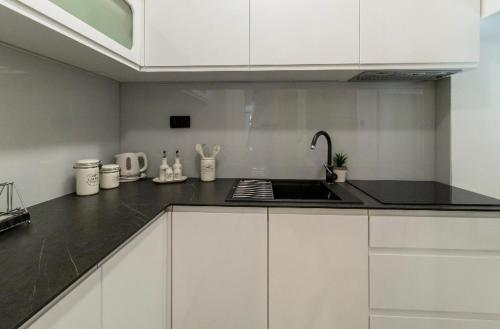 a kitchen with white cabinets and a black counter top at Apartman Roseta in Dubrovnik