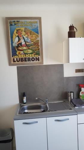 una cocina con fregadero y un cartel en la pared en fleur de garance, en Le Thor