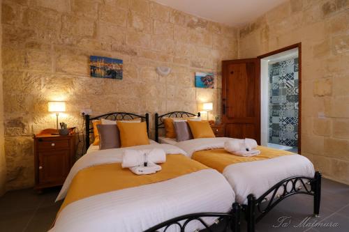 a bedroom with two beds with towels on them at Ta' Matmura Farmhouse in Għarb
