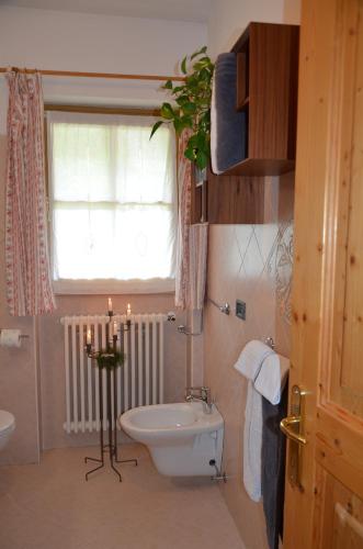 a bathroom with a toilet and a window and a candle at B&B Primavera in Spormaggiore