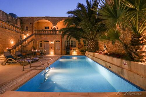 a swimming pool in a courtyard with a house at Ta' Matmura Farmhouse in Għarb