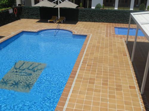 a large swimming pool with a tiled floor and an umbrella at Hotel Santa Anna in L'Estartit