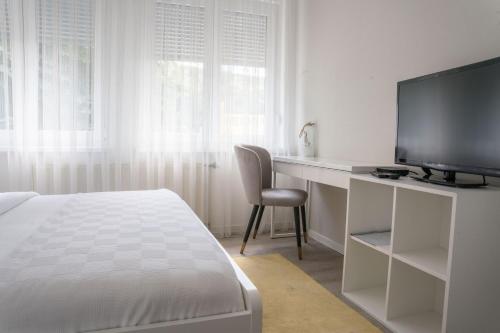 a room with a bed, chair, desk and television at Hotel MOREA in Ljubljana