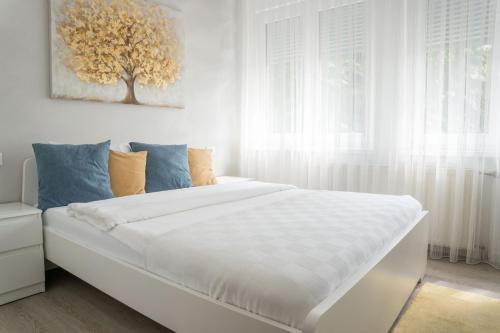 a bedroom with a white bed with a tree painting on the wall at Hotel MOREA in Ljubljana