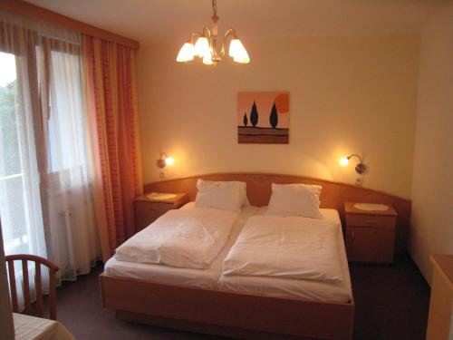 a bedroom with a bed with white sheets and pillows at Strandpension Liane in Sankt Kanzian